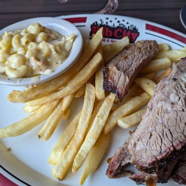 Rib City BBQ plate with sliced brisket, golden fries, and a side of creamy mac and cheese.
