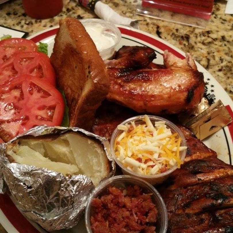Rib City BBQ plate with grilled chicken, ribs, baked potato, Texas toast, and sides.