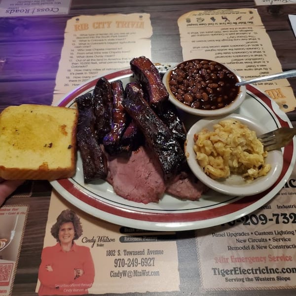 Rib City's BBQ ribs and sliced brisket with sides of baked beans, mac and cheese, and cornbread.