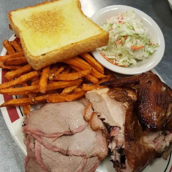 Rib City's BBQ plate with sliced beef, chicken, sweet potato fries, coleslaw, and Texas toast.